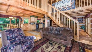 A spacious living area with a high ceiling, wooden beams, a staircase, and a view of the outdoors. - View Private Hot Tub Pool Table Fireplace Relax (Sevierville)