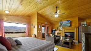 A cozy log cabin room with a bed, a sofa, a fireplace, and a television. - Great View Location Studio Log Cabin Hot Tub (Gatlinburg)