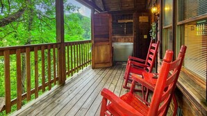 Een houten terras met rode stoelen, een plafondventilator en een uitzicht op weelderige begroeiing.