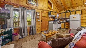Een knus chalet met houten wanden, een keuken, een woonruimte met een bank en een televisie.