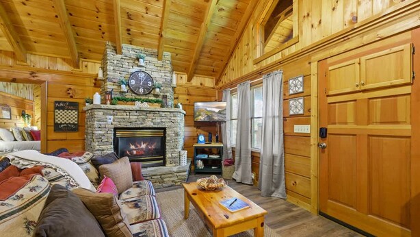 L’intérieur d’un chalet confortable, avec une cheminée en pierre, des meubles en bois et une grande porte en bois.