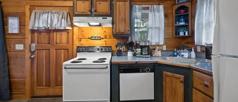 A kitchen with wooden cabinets, a stove, a dishwasher, and a refrigerator.