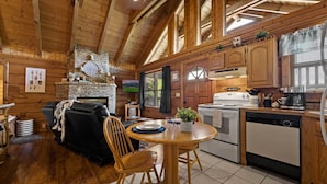 A cozy cabin interior with a dining area, kitchen, and a fireplace.
