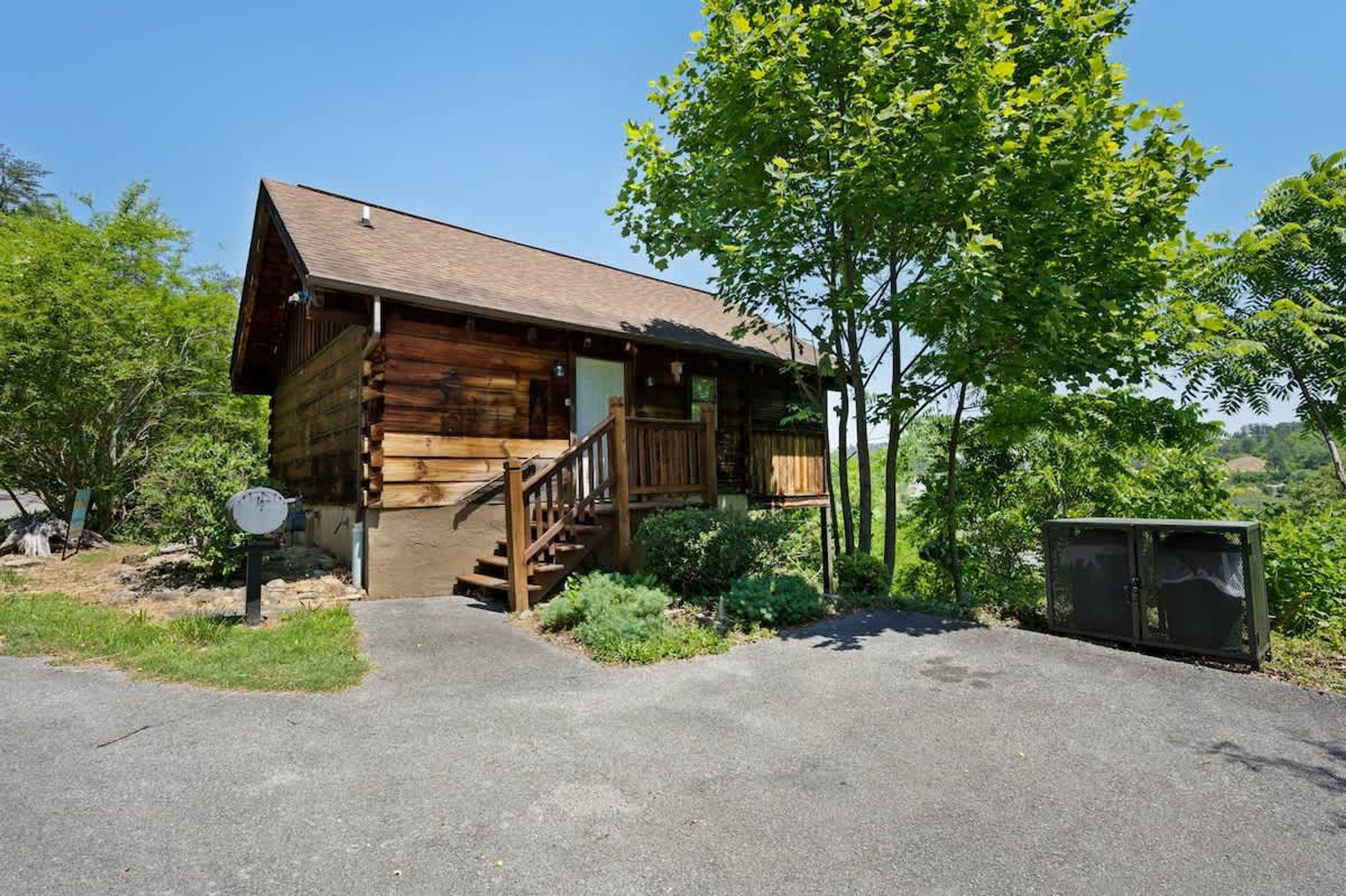 A wooden cabin with a porch and stairs leading to the entrance.