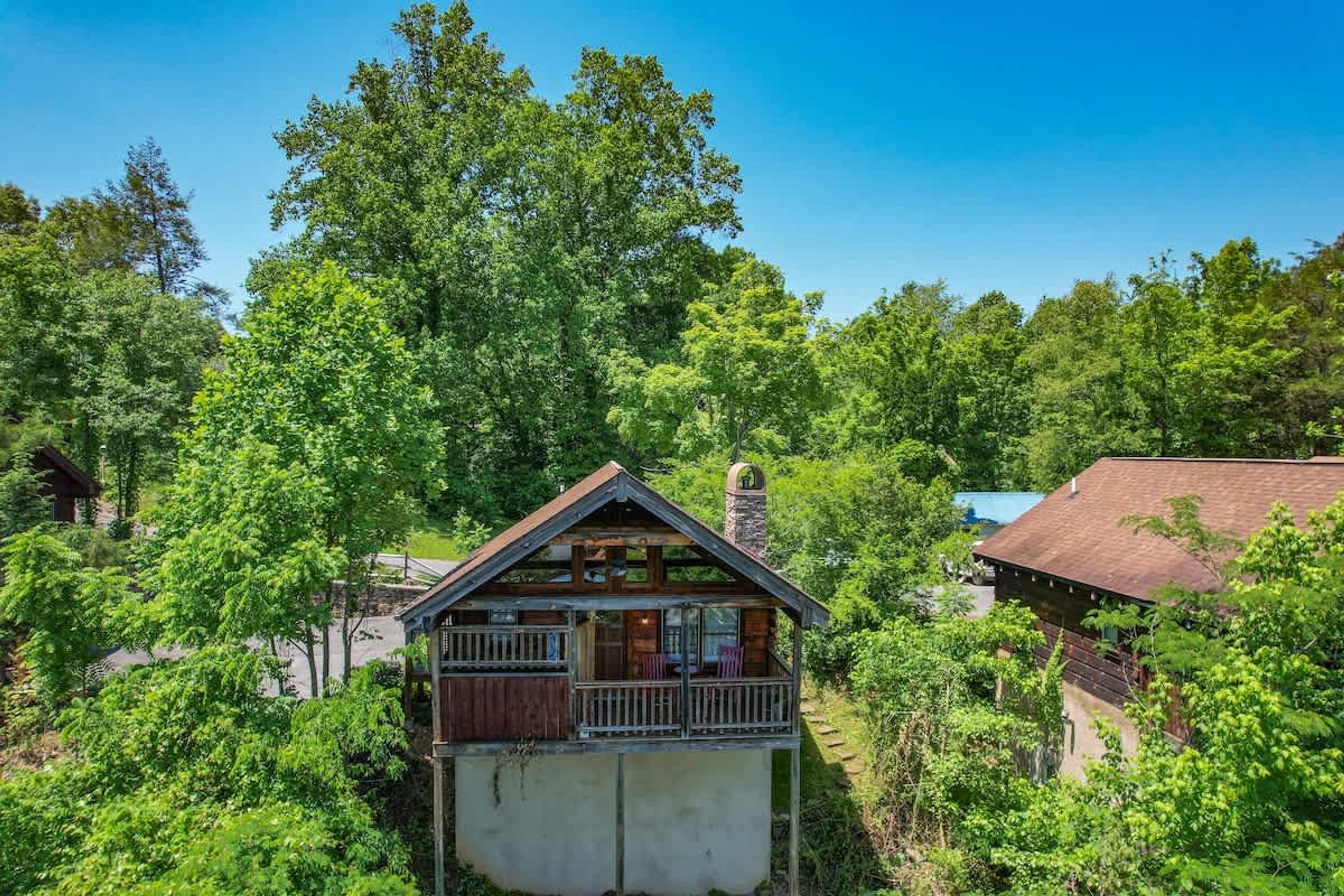 Une cabane dotée d’un balcon, entourée d’une forêt dense.