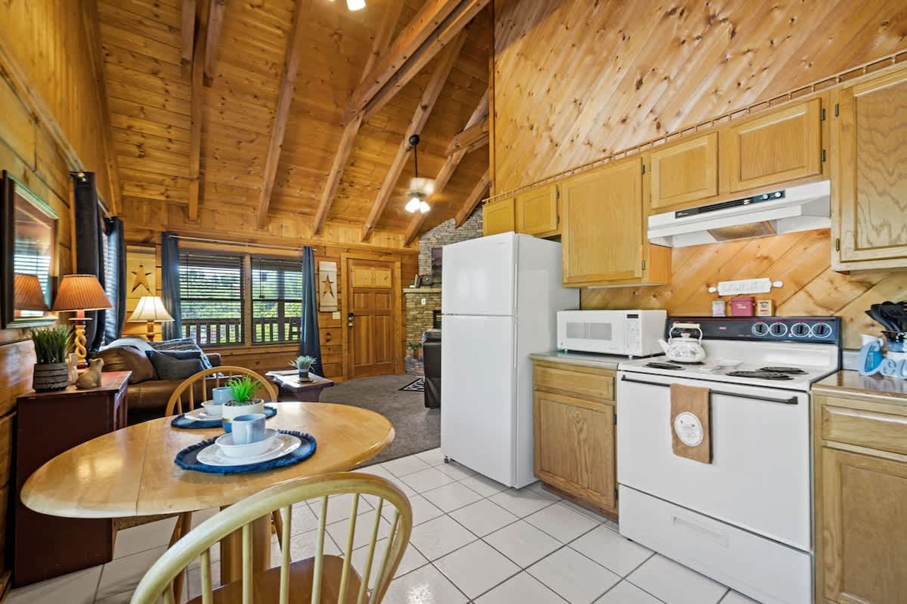 A wooden cabin interior with a kitchen featuring a refrigerator, microwave, stove, and wooden cabinets.