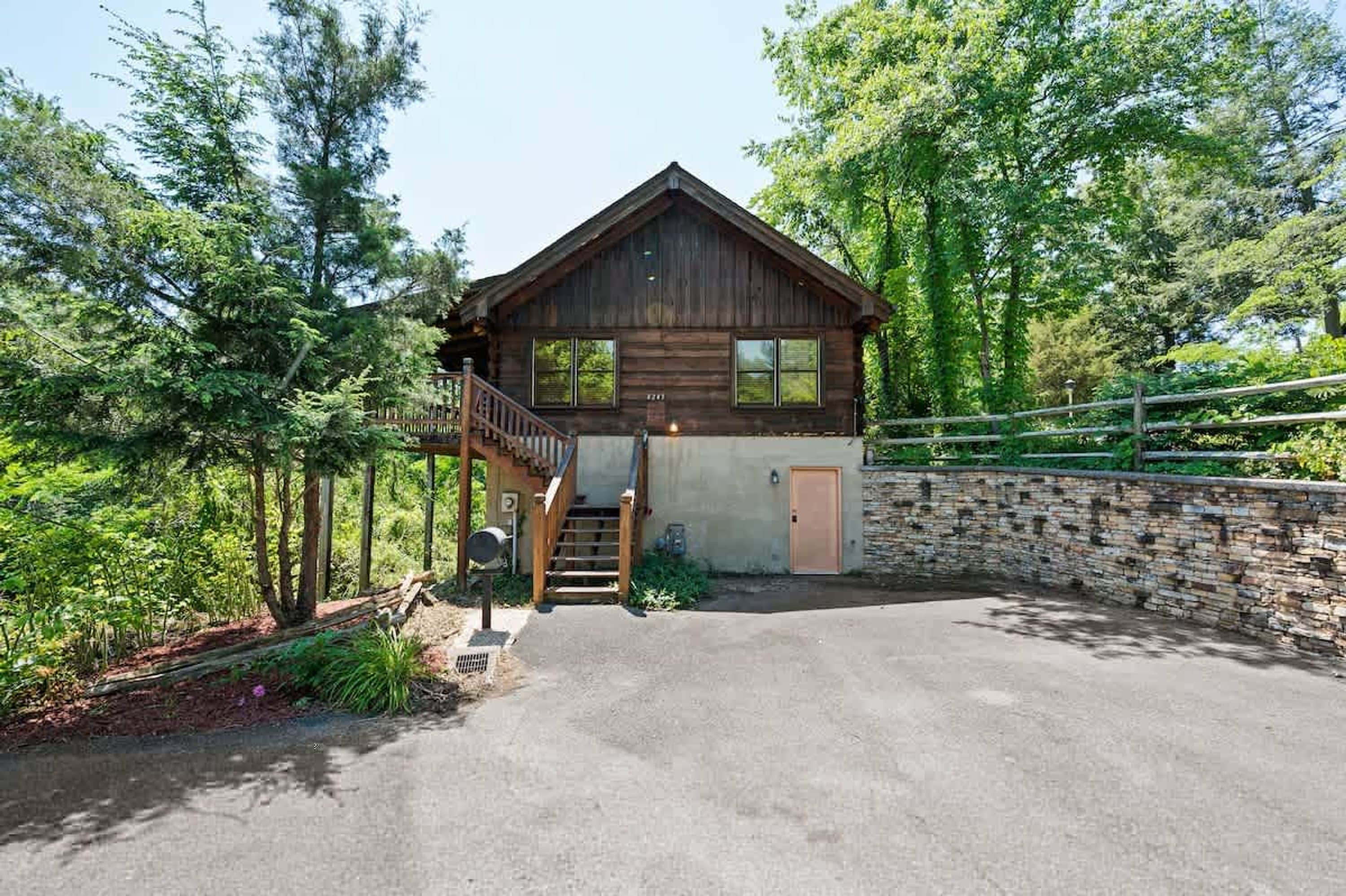 A two-story log cabin with a wooden staircase leading to the upper level.