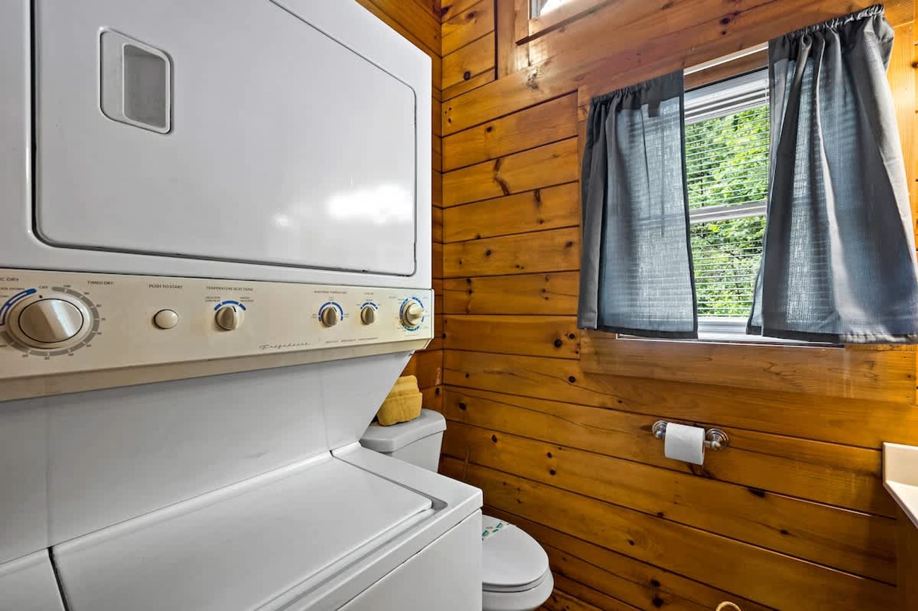 Ein kleiner Raum mit Holzwänden, einer weißen Waschmaschine und einem WC.