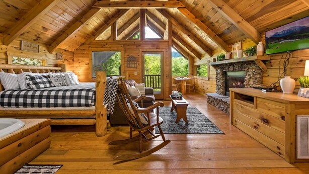 A cozy log cabin interior with a loft bedroom, a fireplace, and a dining area. - Private Studio Log Cabin Hot Tub Fireplace Relax (Sevierville)