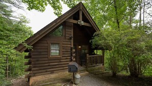 A rustic log cabin with a porch, a mailbox, and a stone foundation. - Private Studio Log Cabin Hot Tub Fireplace Chill (Sevierville)
