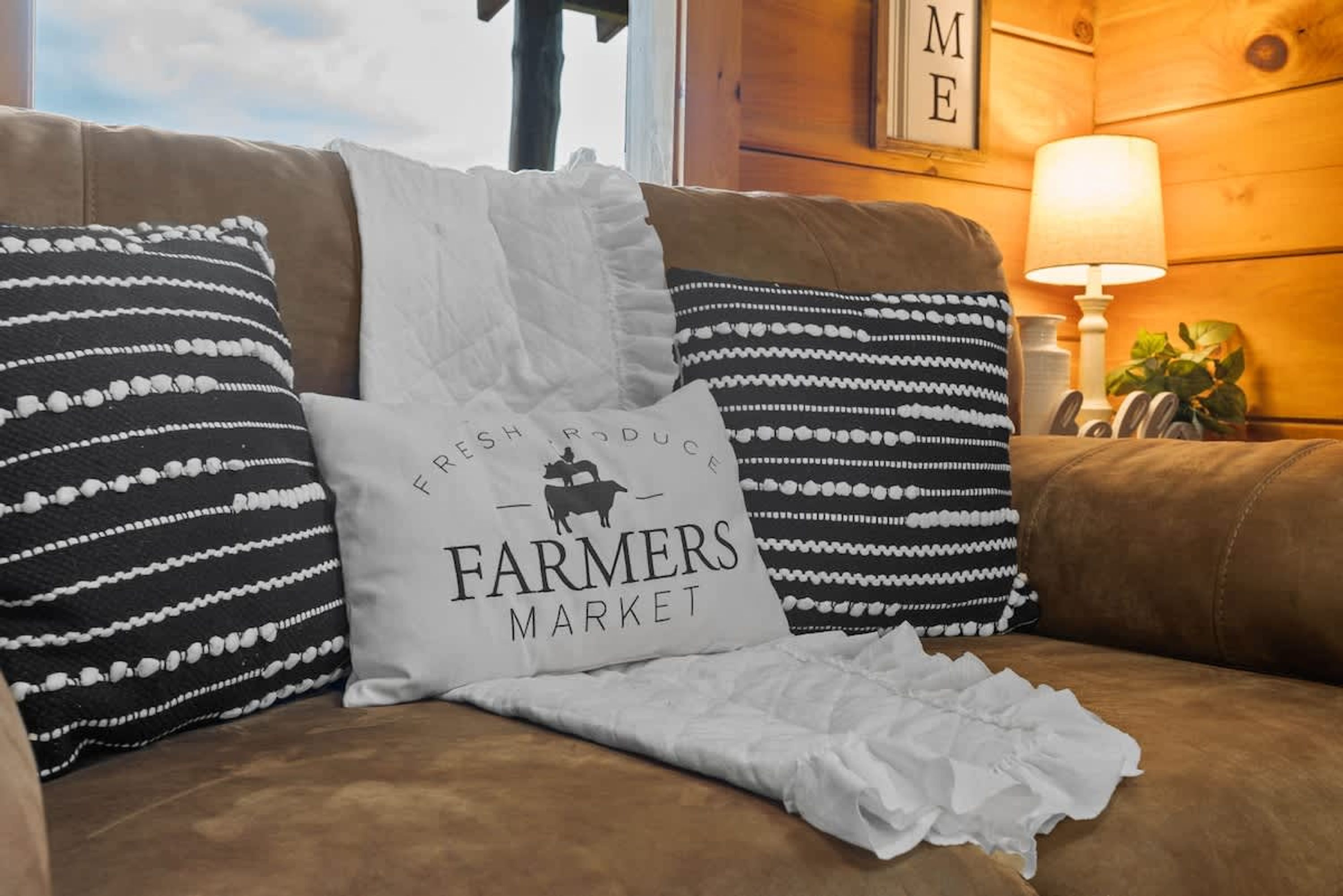 A brown leather couch with patterned pillows and a white pillow with text.