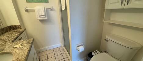 A bathroom with a toilet, a sink, a towel rack, and a green sign on the wall.