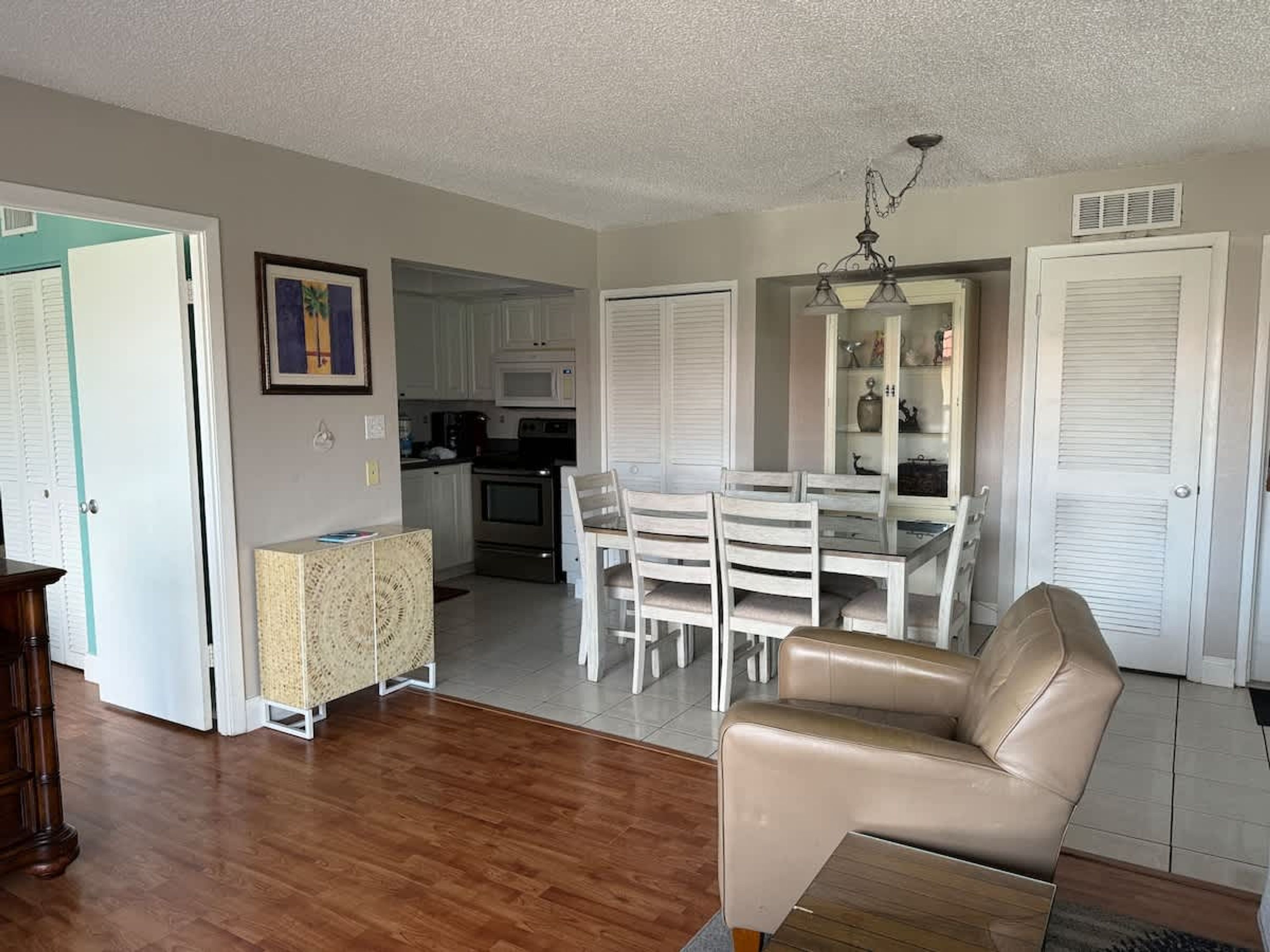 A spacious living room with a dining area, a kitchen in the background, and a beige leather sofa.