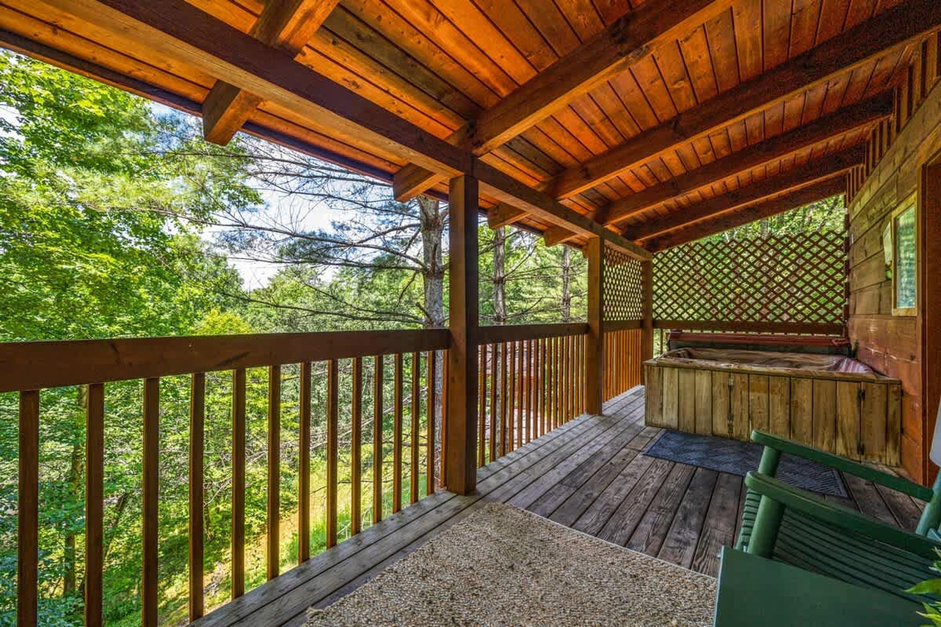 Une terrasse en bois avec une rambarde en bois, un banc en bois et un mur en treillis.