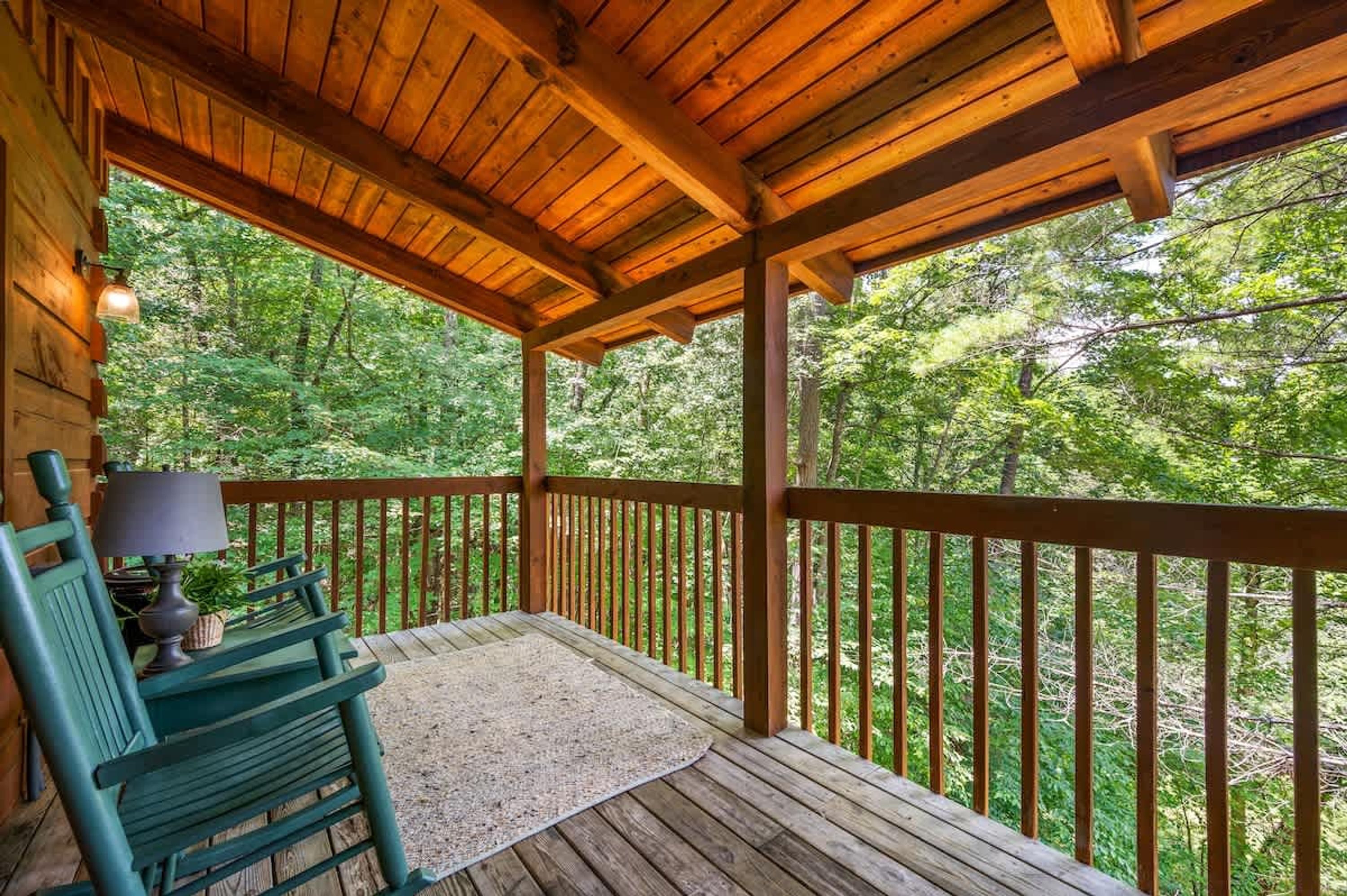 Une terrasse en bois avec une rambarde, un banc et une lampe.