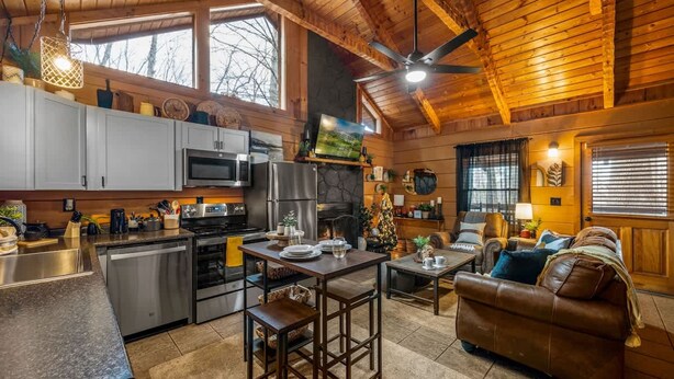 A cozy cabin interior with a kitchen, dining area, and living room. - Location-quiet-hottub-fireplace (Sevierville)