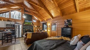 A cozy cabin interior with a kitchen, dining area, and a large bed. - Location-quiet-hottub-fireplace (Sevierville)