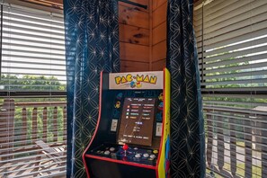 Máquina de arcade Pac-Man numa varanda com vista para o exterior.