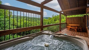A hot tub on a wooden deck with a view of a forested landscape. - View-location-hot Tub-pool Table-3 Fireplaces (Sevierville)