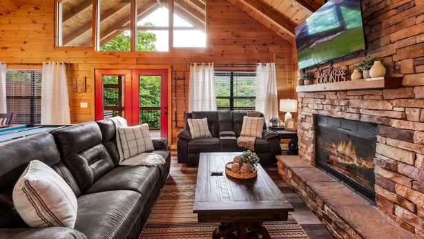 A cozy living room with a fireplace, leather sofas, and a large TV on the wall. - View-location-hot Tub-pool Table-3 Fireplaces (Sevierville)