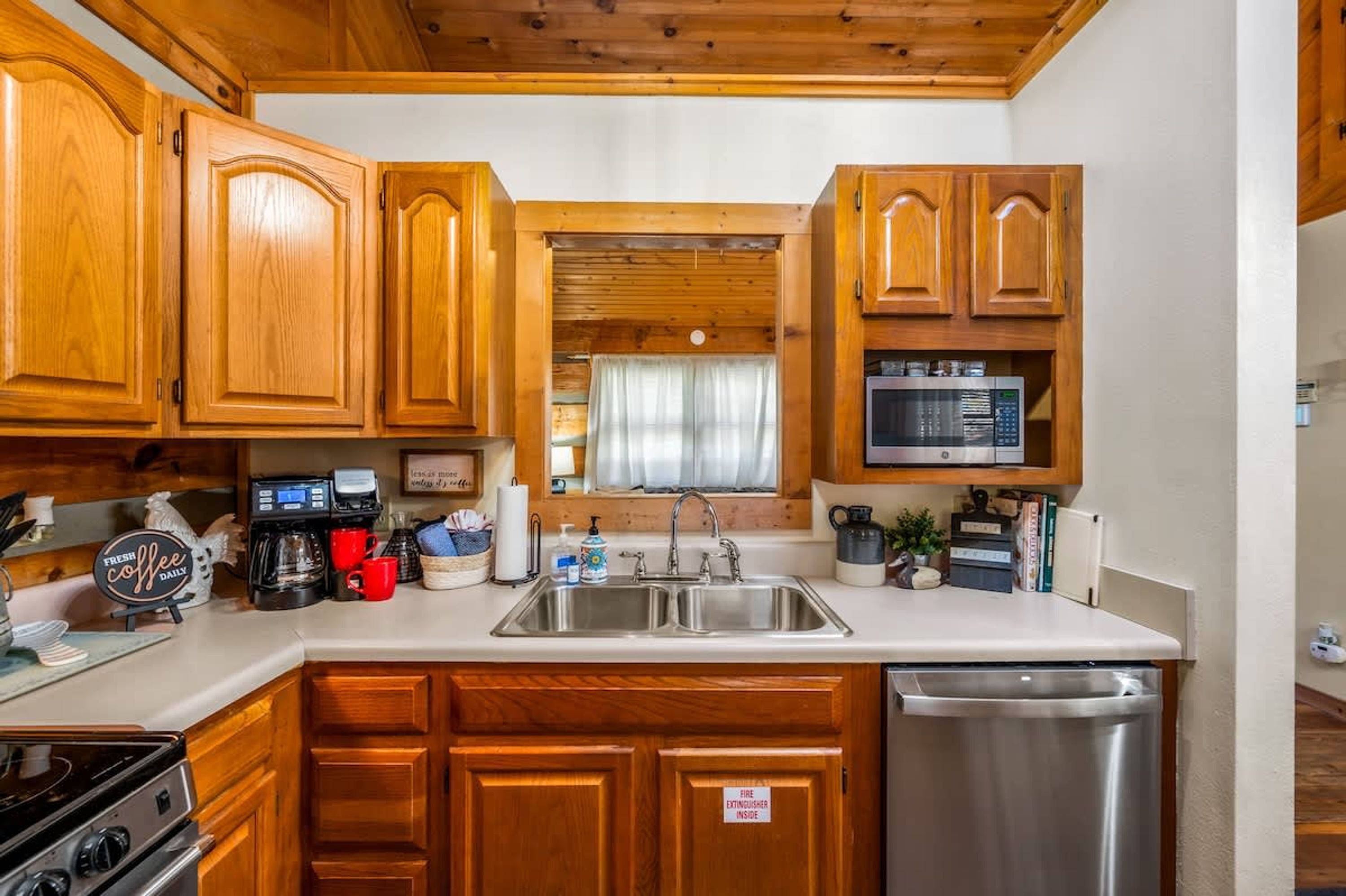 A kitchen with wooden cabinets, a stainless steel sink, a microwave, a coffee maker, and a dishwasher.