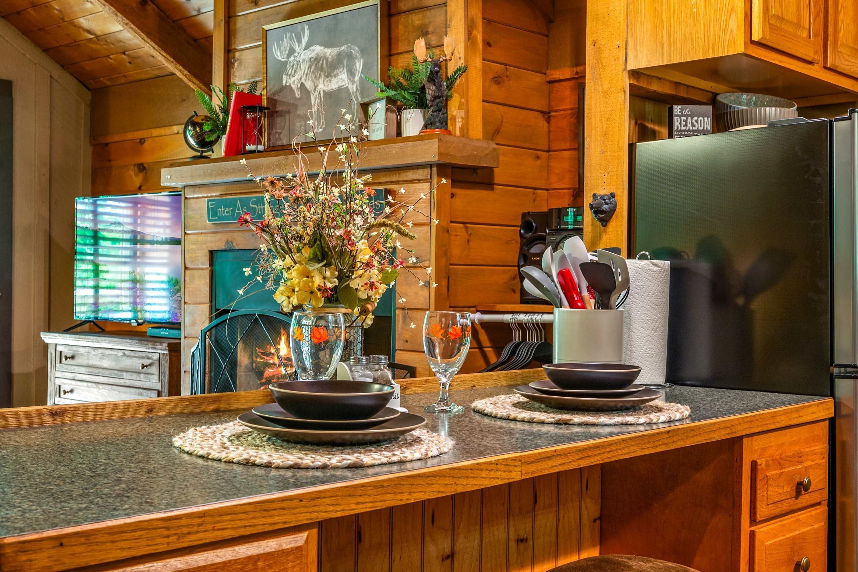 A wooden cabin kitchen with a granite countertop, a vase with flowers, and a sign that says "Enter As Soon As Possible".