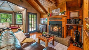 A cozy log cabin interior with a fireplace, leather sofa, and a dining area. - Secluded Cabin in the Woods-hot Tub-quiet-fireplace-honeymoon (Sevierville)