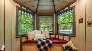 A cozy corner with a red cushioned bench, a plaid blanket, and a basket of folded blankets. - Secluded Cabin in the Woods-hot Tub-quiet-fireplace-honeymoon (Sevierville)