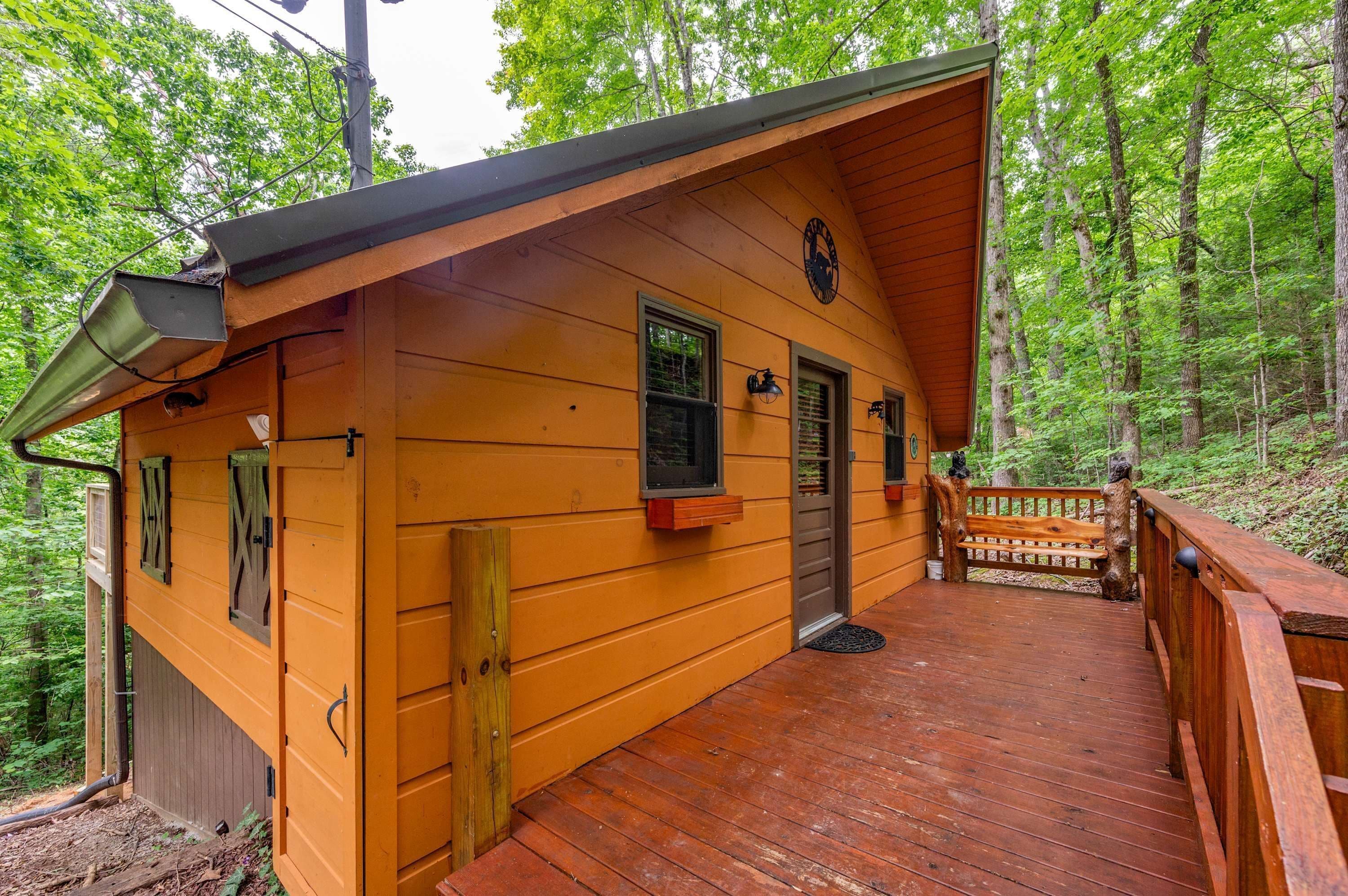 Une cabane en bois dotée d’une terrasse, entourée d’arbres.