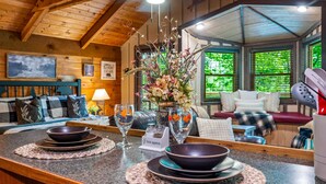 A cozy cabin interior with a wooden ceiling, a dining area with a table set for two, and a living room with a sofa and a fireplace. - Secluded Cabin in the Woods-hot Tub-quiet-fireplace-honeymoon (Sevierville)