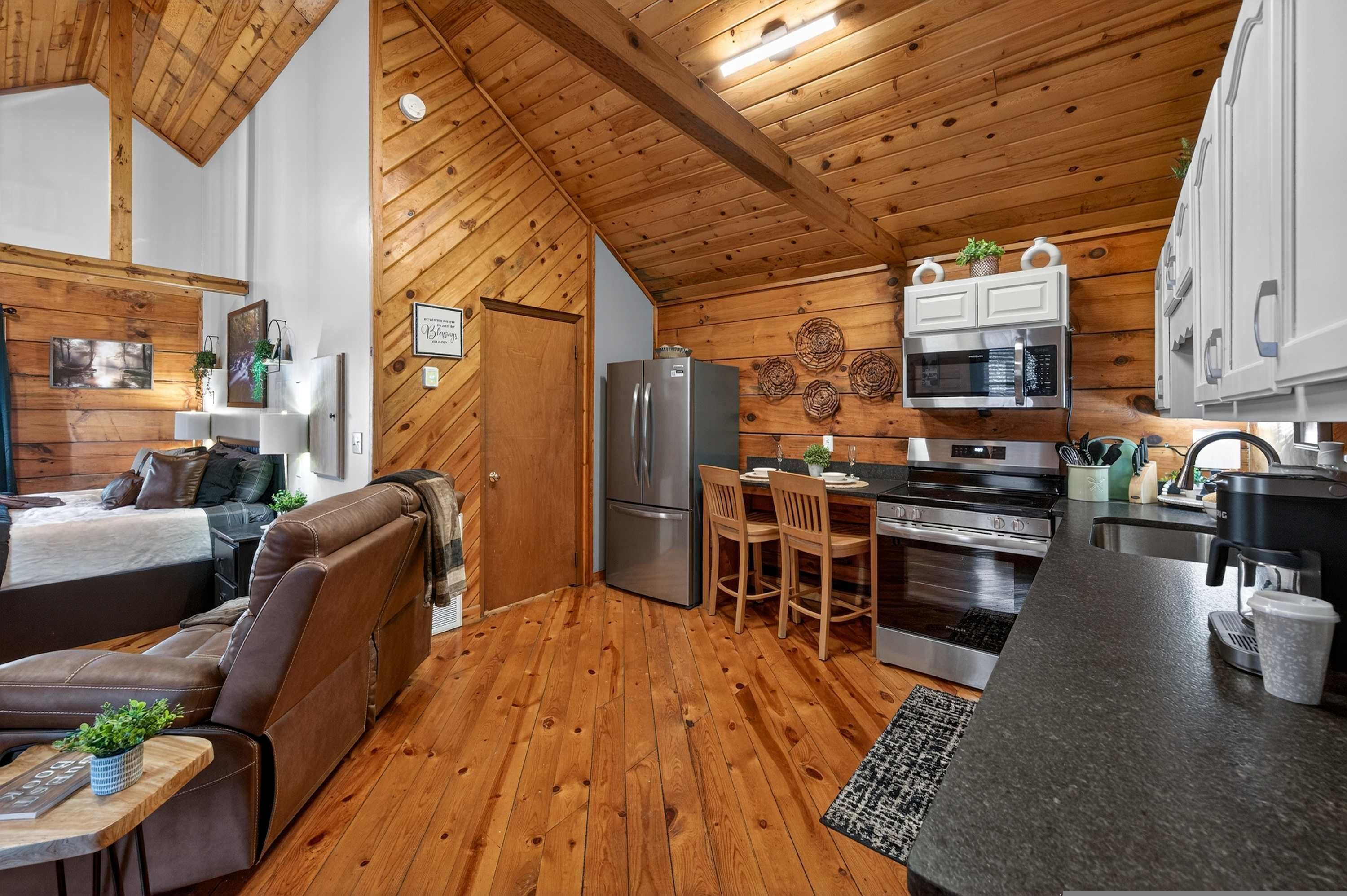 A compact living space with a kitchenette, wooden ceiling, and a cozy seating area.