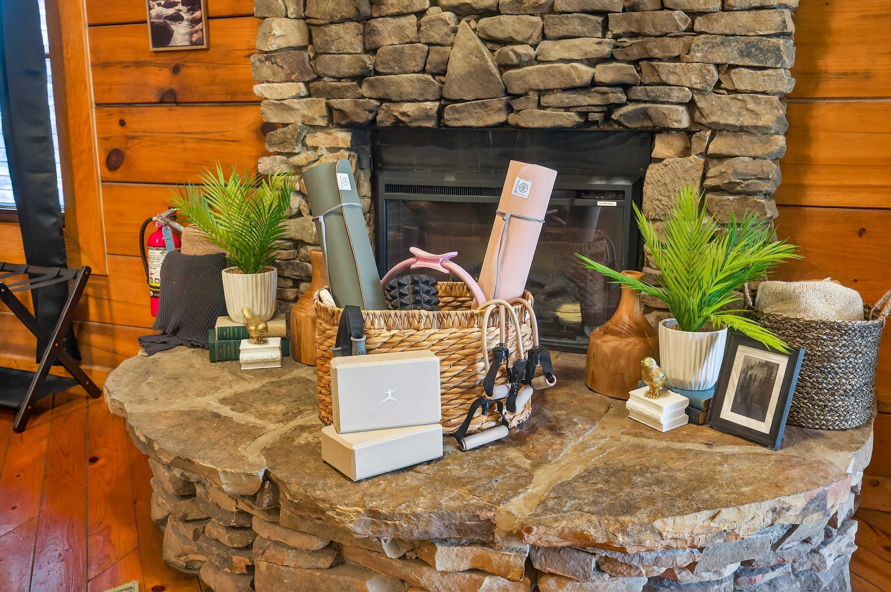 A stone fireplace with a stone wall behind it, a laptop on a stone table, and various plants and items on the table.