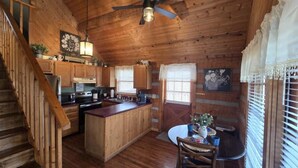 A wooden cabin interior with a kitchen, dining area, and a staircase. - Hot Tub Arcade Fireplace Honeymoon Hiking Fun (Sevierville)