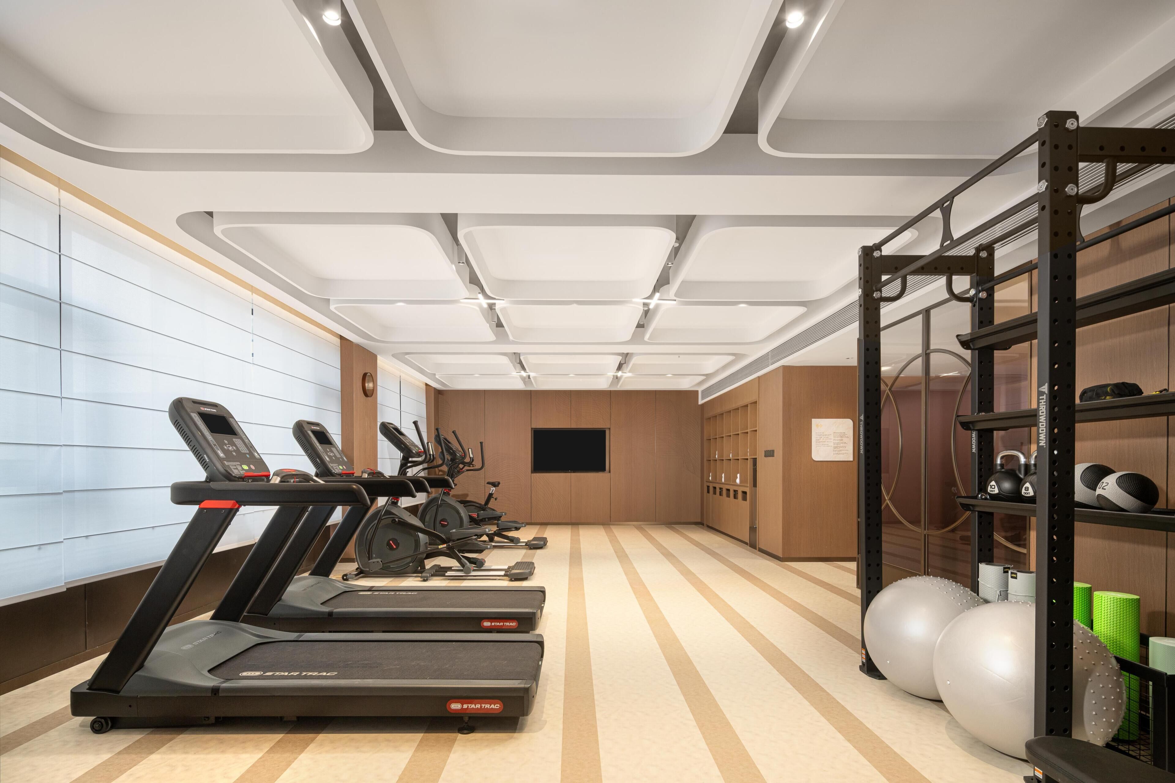Un gimnasio con cintas de correr, elípticas y pelotas de ejercicio.