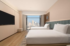 A hotel room with a large bed, a flat-screen TV, a city view, and a small seating area. - Hilton Garden Inn Dali Erhai Park (Dali)