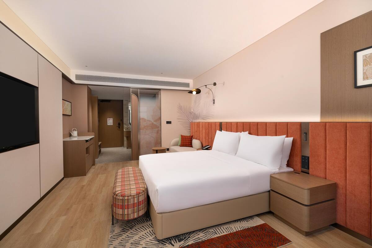 Une chambre d’hôtel moderne avec un grand lit, des tables de chevet, un petit bureau et un téléviseur.