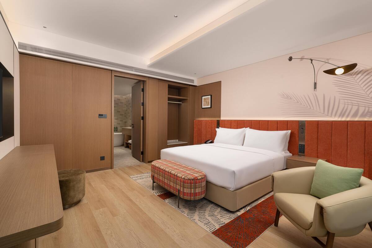 Une chambre d’hôtel moderne équipée d’un lit, d’un bureau, d’une chaise et d’une armoire.