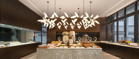 A modern hotel lobby with a marble reception desk, a large window, and a decorative ceiling light fixture.