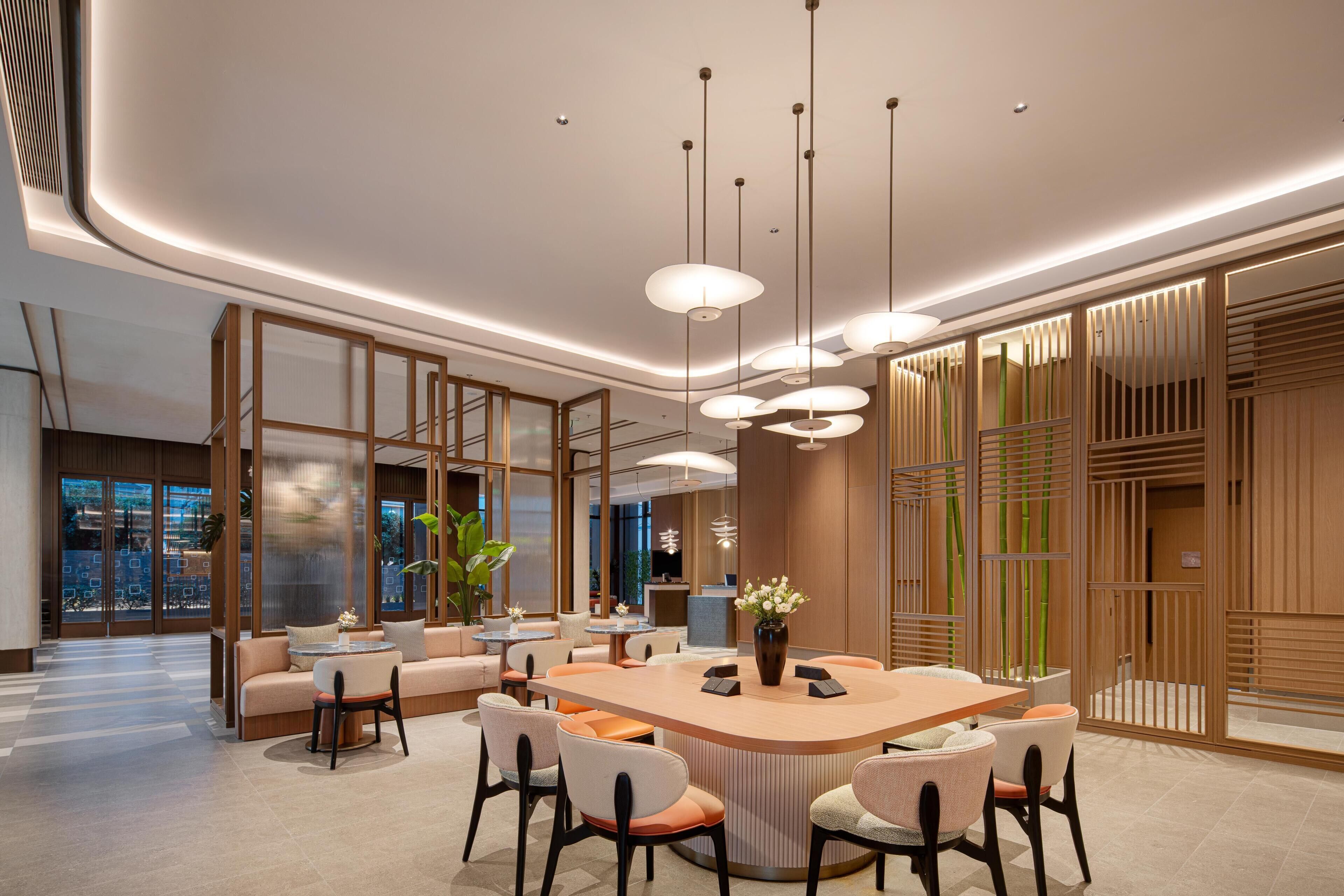 Eine moderne Hotelhalle mit einer zentralen Inselloge, Sitzgelegenheiten und einer Rezeption.