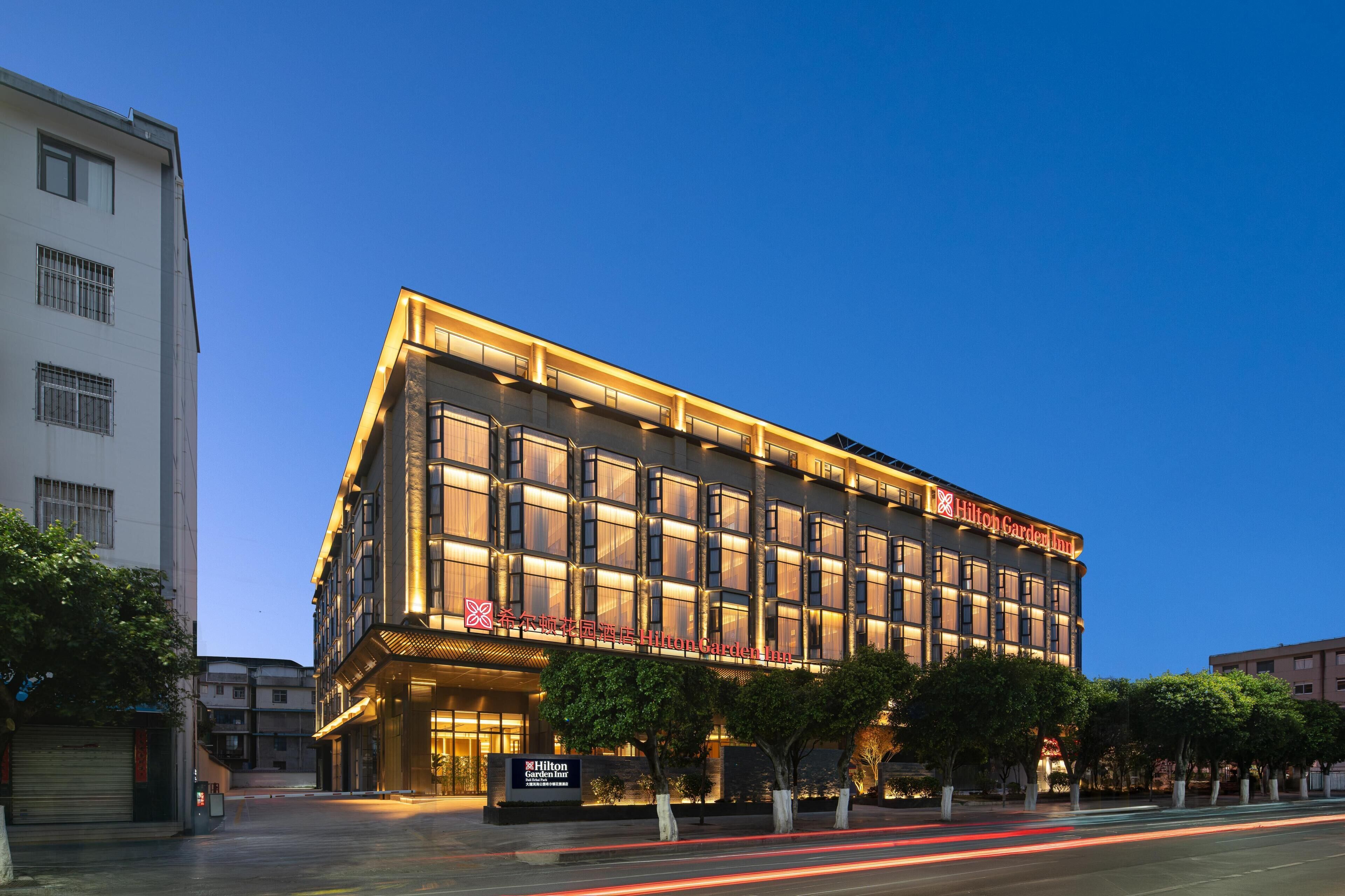 A multi-story hotel with a prominent sign, large windows, and a well-lit facade.