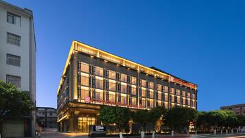 A multi-story hotel with a prominent sign, large windows, and a well-lit facade.