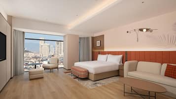 A modern hotel room with a large bed, a sofa, a small table, and a TV.