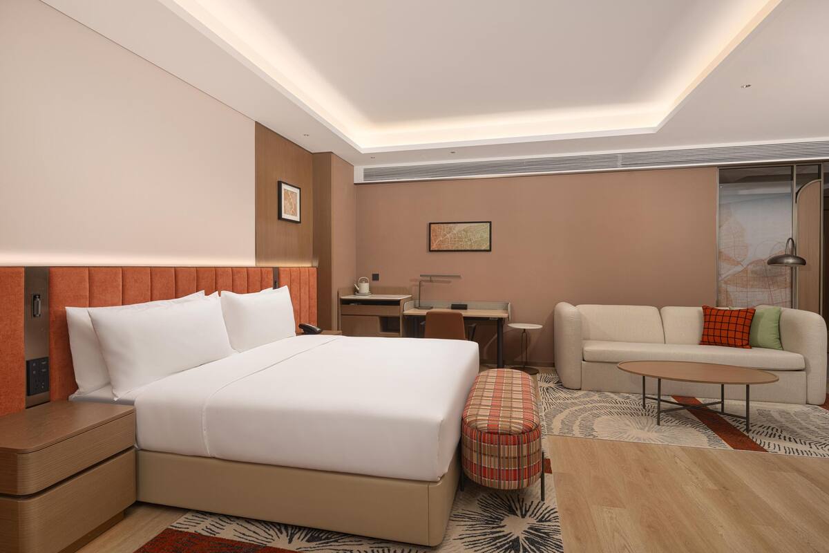 Une chambre d’hôtel avec un lit, un bureau, un canapé et une table basse.
