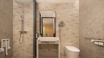 Un baño moderno con ducha, lavamanos, inodoro y espejo.