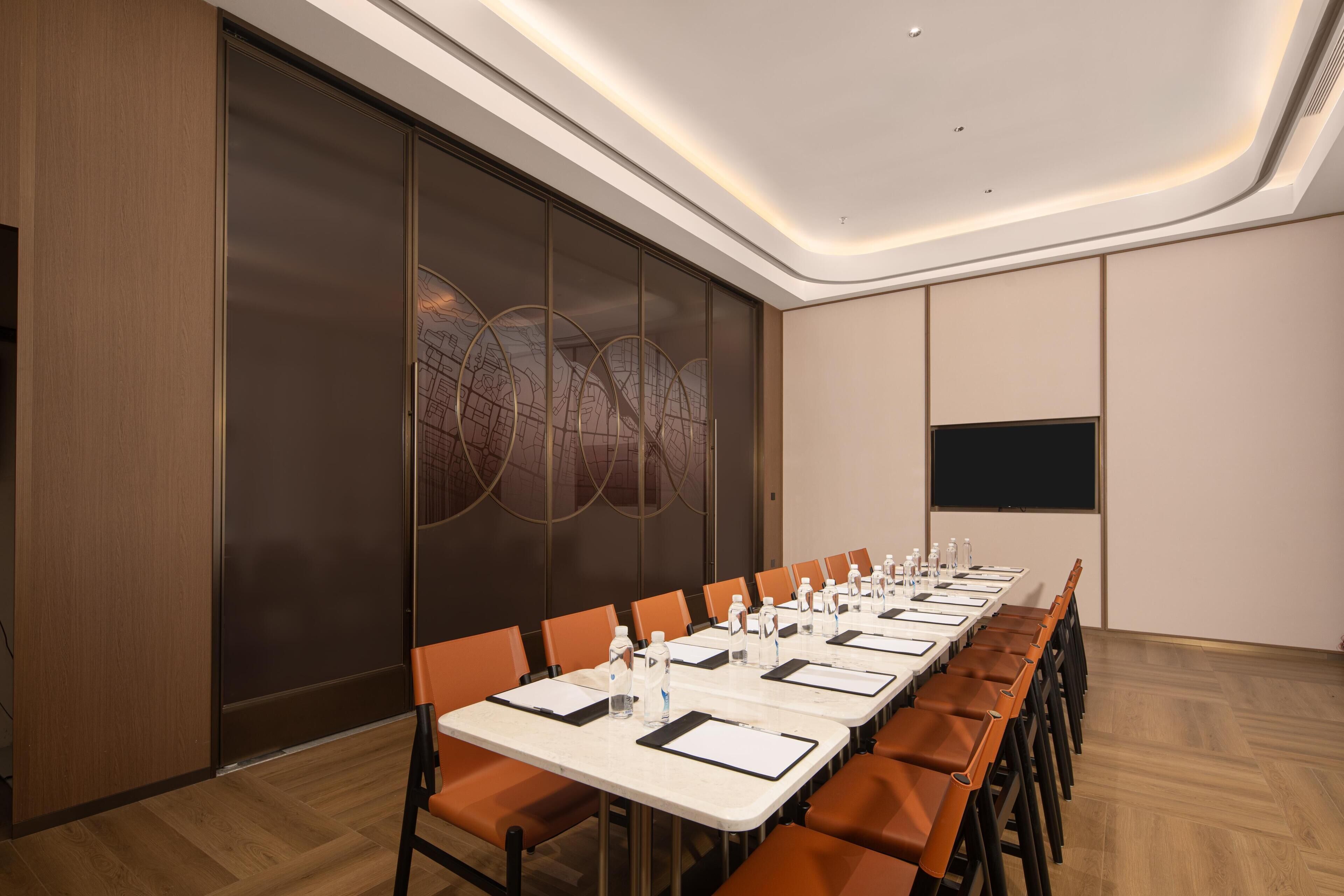 A conference room with a long table, chairs, and a projector screen.