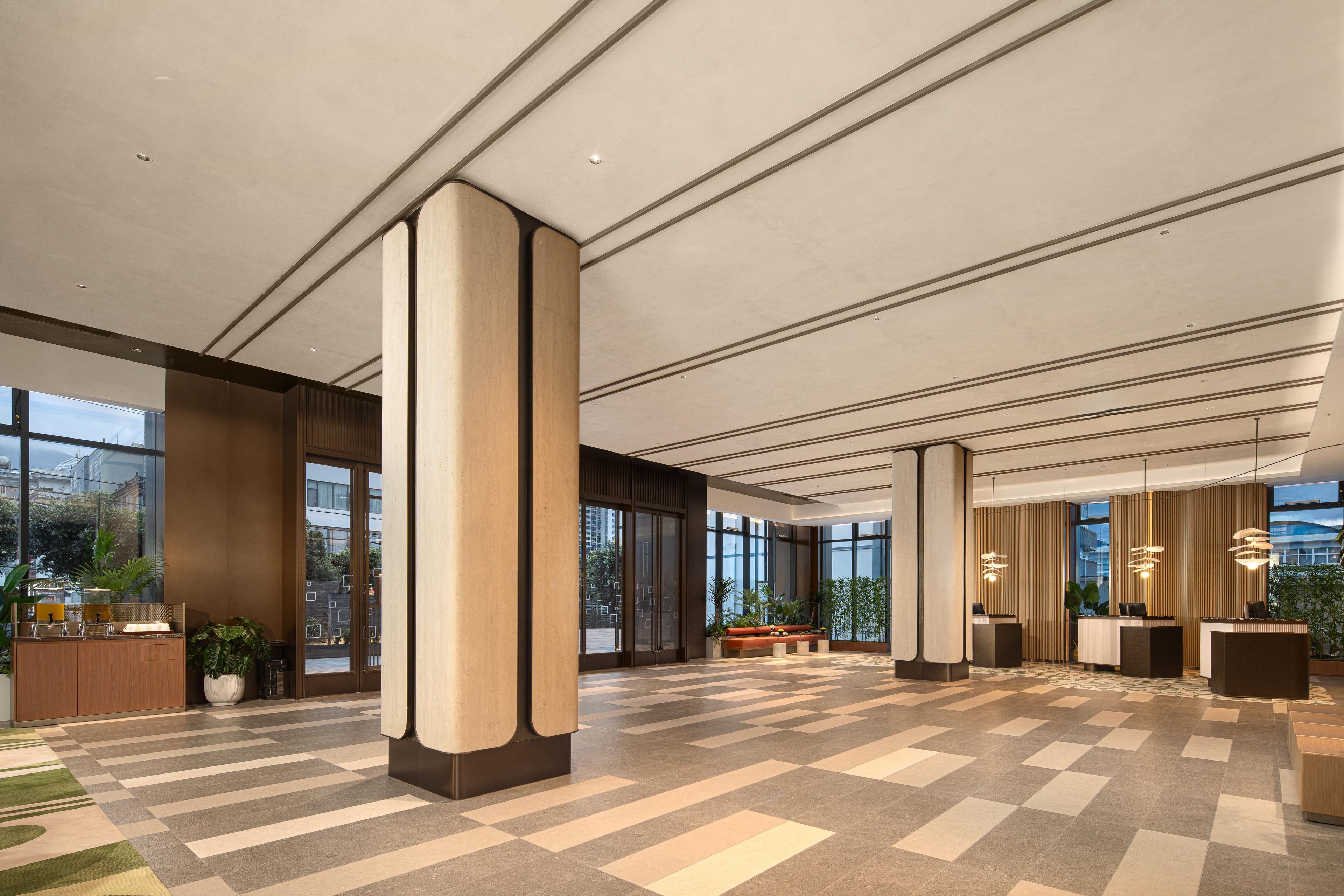 Eine geräumige Lobby mit großen Fenstern, einem Schachbrettfußboden und einer Rezeption.