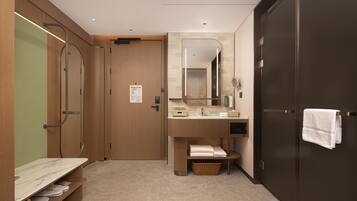 Un baño moderno con tocador de madera, un espejo, toallero y zona de ducha.