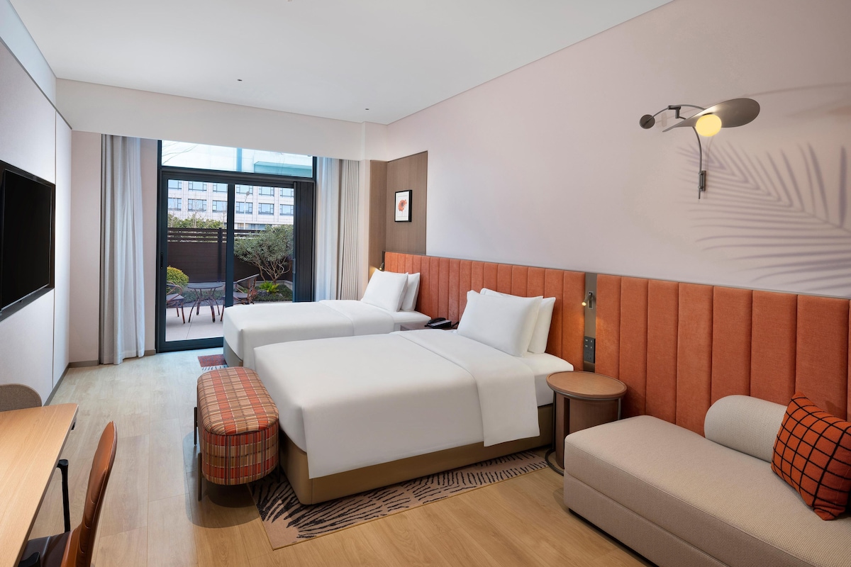 A hotel room with two beds, a sofa, a small table, and a TV.