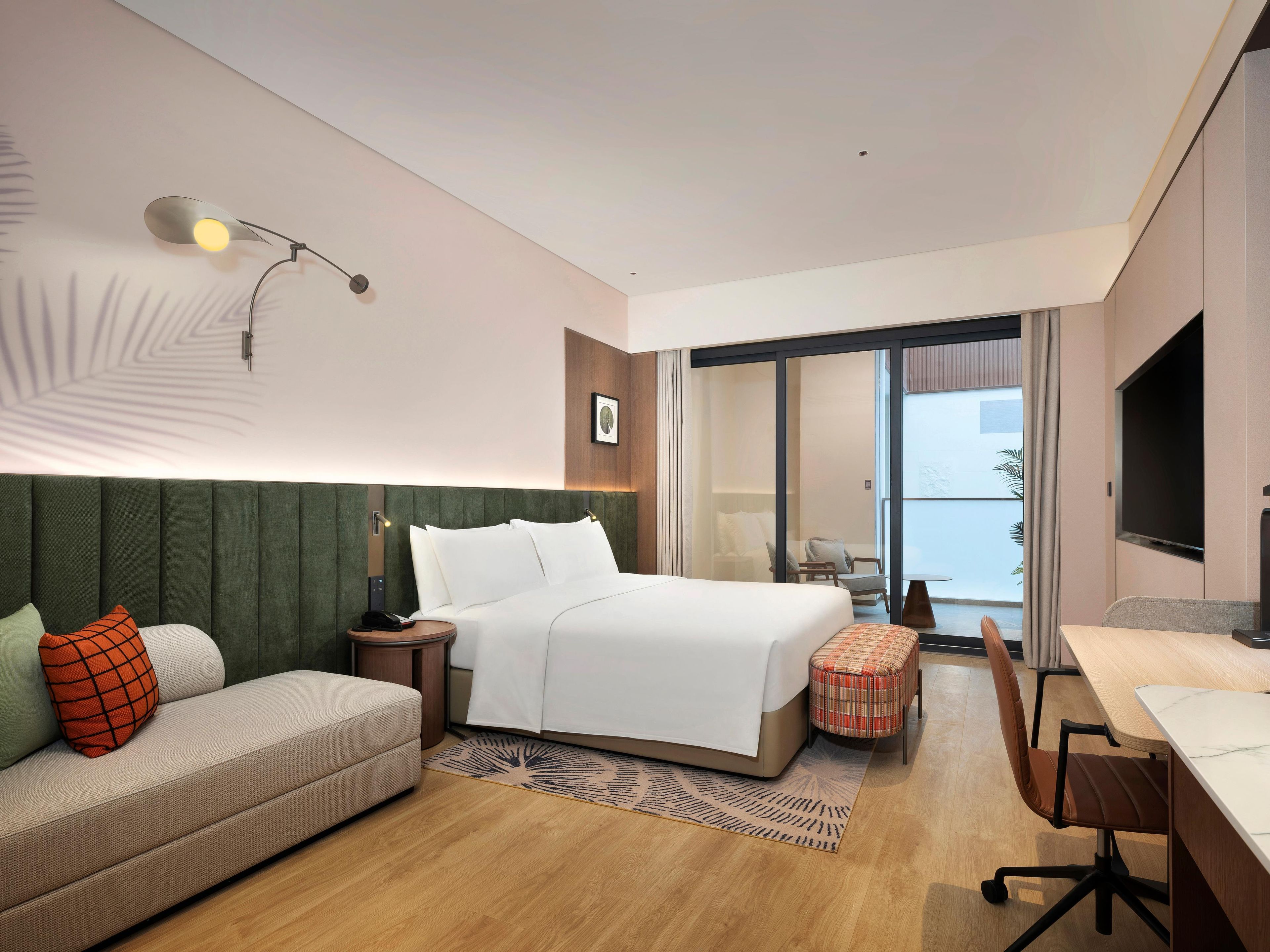Een hotelkamer met een bed, een bank, een bureau en uitzicht.