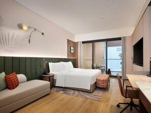 A hotel room with a bed, a sofa, a desk, and a view of the outside. - Hilton Garden Inn HuZhou Nanxun Water Town (Suzhou)